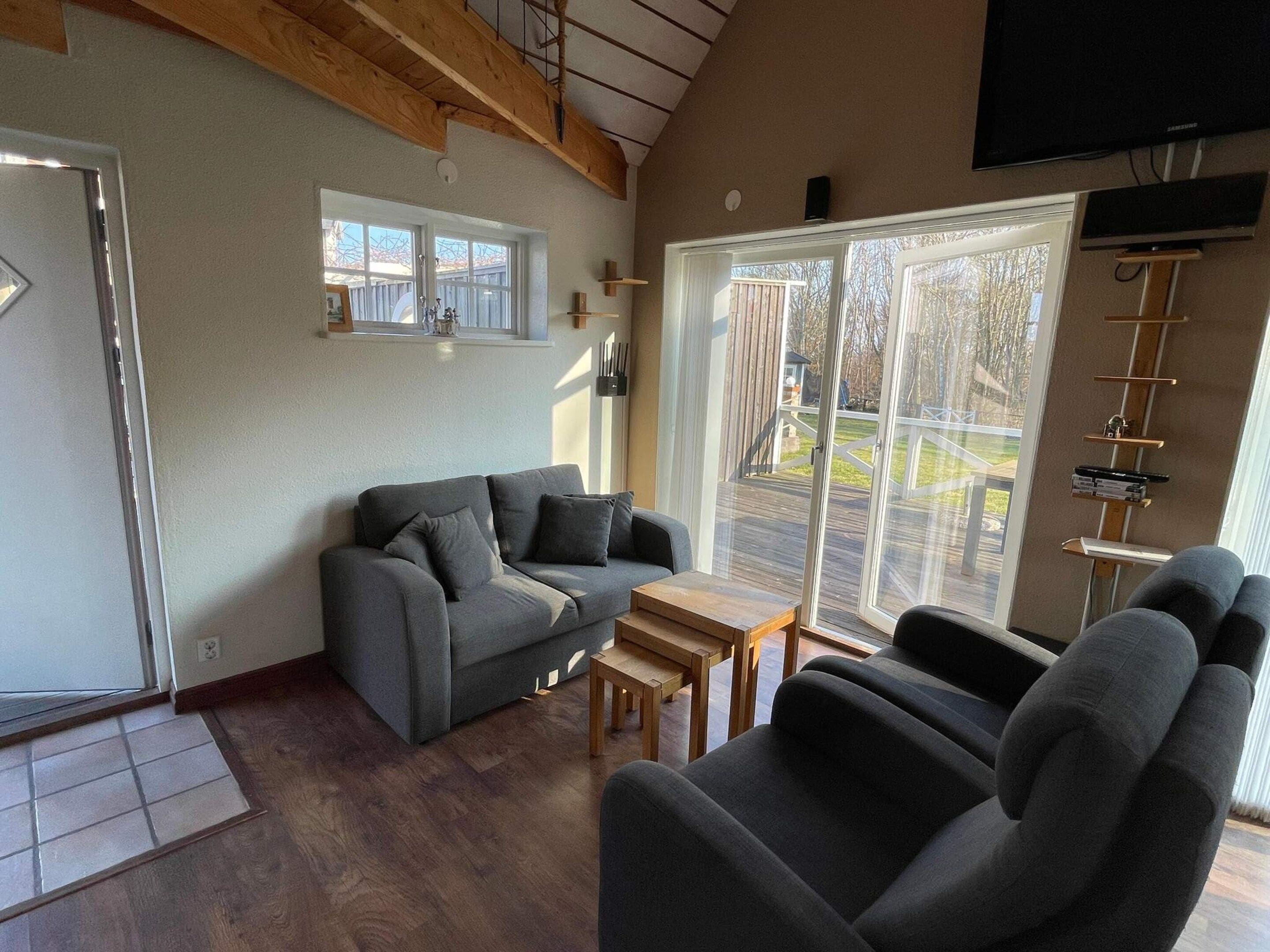 A living room with a grey sofa, a wooden coffee table, and a TV mounted on the wall.