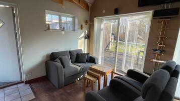 A living room with a grey sofa, a wooden coffee table, and a TV mounted on the wall.