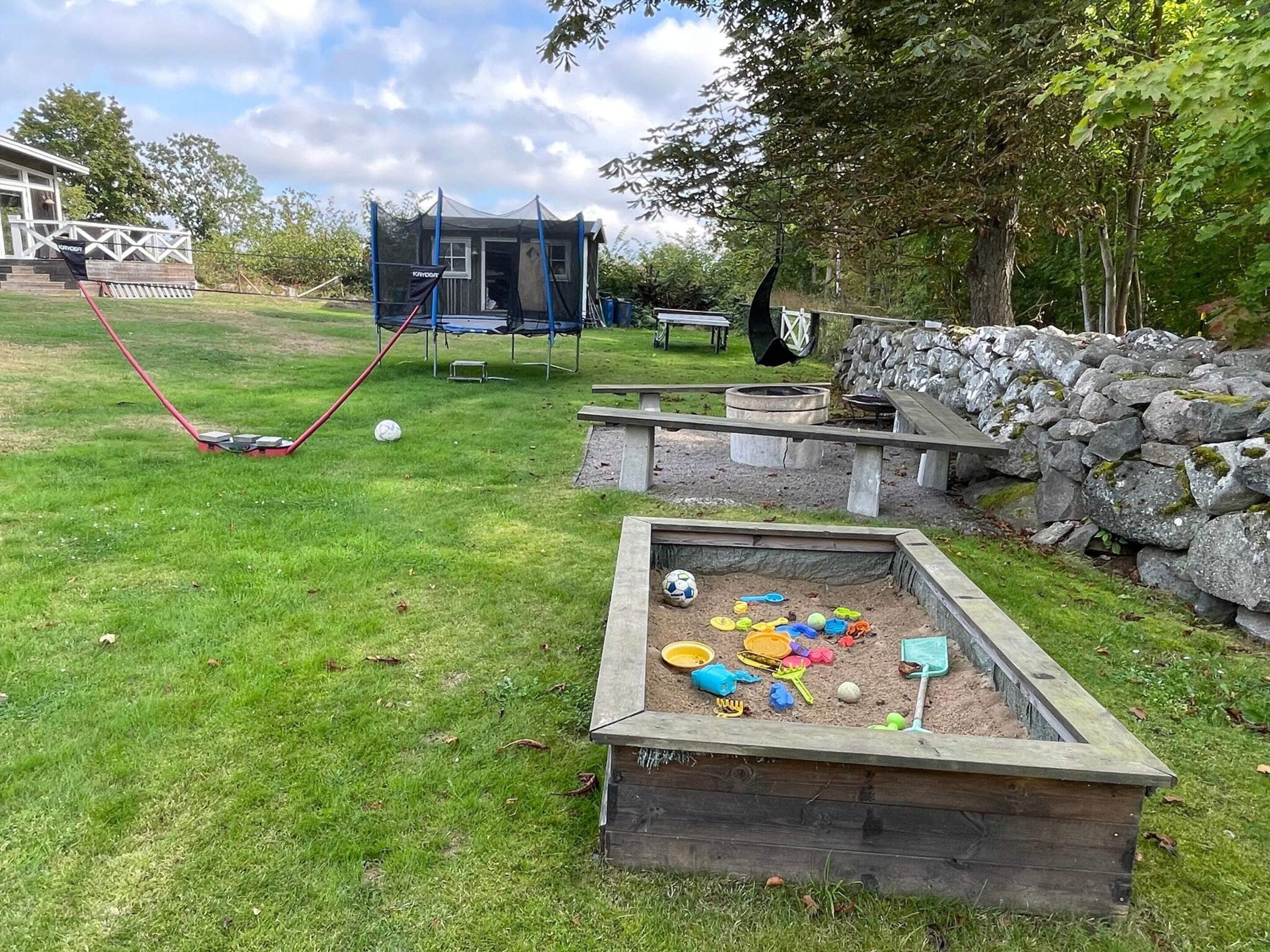 A playground with a swing set, a sandbox, and a small building structure.