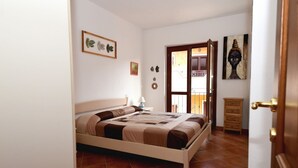 A bedroom with a bed, a nightstand, a door, and a view of the outside. - Casa di Adriana by Rentbeat (Palau)