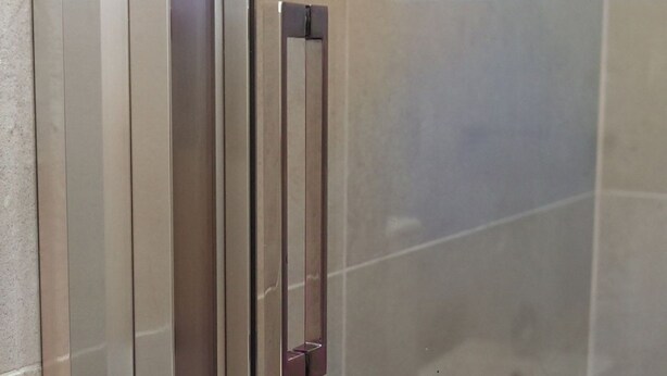 Uma maçaneta metálica em uma porta, provavelmente para um banheiro ou ambiente semelhante.