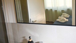 Ein Badezimmer mit Spiegel, Handtuchspender und einem Bett mit Handtüchern.