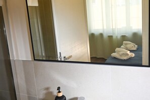 Un bagno con uno specchio, un distributore di asciugamani e un letto con asciugamani.