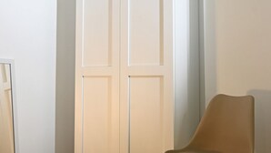 Ein Zimmer mit einer geschlossenen weißen Tür, einem beigen Sessel und einer weißen Wand.