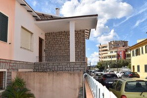 Ein Gebäude mit einer Stein-Fassade, einem Balkon und einem Parkplatz mit Autos.