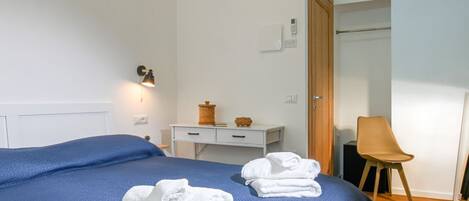 Una habitación de hotel con cama, escritorio, silla y armario.