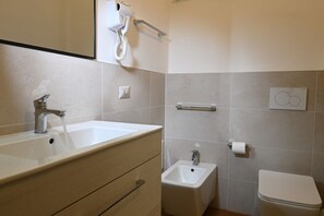 Ein Badezimmer mit Waschbecken, Bidet, Toilette und Handtuchhalter.