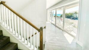 A staircase with white railings and wooden steps leading to a balcony with a view of the ocean. - Luxury Home with Pool, Spa and Rooftop! (Holmes Beach)