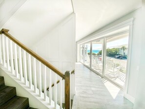 Eine Treppe mit weißen Geländern und Holzstufen führt zu einem Balkon mit Blick aufs Meer.