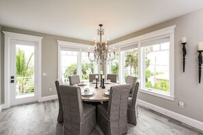Ein Esszimmer mit einem runden Tisch, sechs Stühlen und einer Chandeliebre.