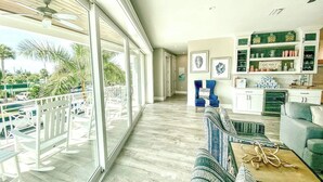 A spacious living area with a balcony, a kitchen area, and a dining space. - Luxury Home with Pool, Spa and Rooftop! (Holmes Beach)