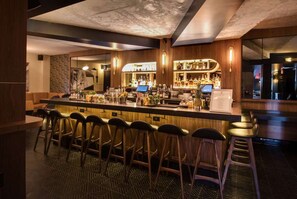 A bar area with a long counter, multiple stools, and a variety of bottles and glasses. - Near Madison Square Park | Rooftop Bar. Restaurant (New York)