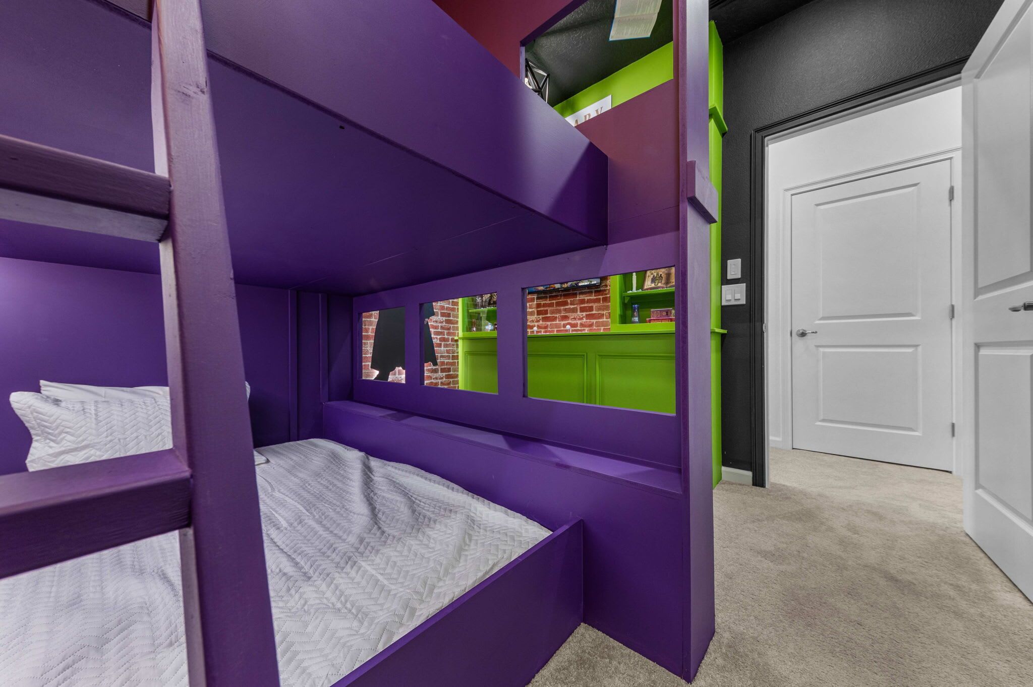 Una cama litera con estructura morada y una ventana que da a un muro de ladrillo.
