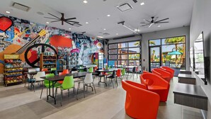 A vibrant cafe with colorful chairs, a mural wall, and a view of an outdoor pool area. - 5BR 5BA Paradiso Grande - Walk to Seaworld 10507 (Orlando)