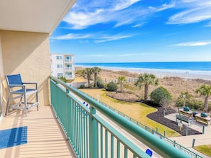 A balcony with a view of the beach, a chair, and a table with outdoor seating. - Windy Hill Dunes 205 (North Myrtle Beach)