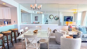 Una cocina moderna con una mesa de comedor de vidrio, sillas blancas y una isla central con taburetes.