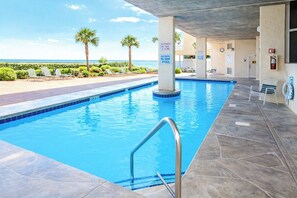 Une piscine avec vue sur l’océan, un poste de surveillance pour les sauveteurs et un panneau indiquant l’emplacement de la piscine.