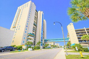 A multi-story hotel with balconies, a pedestrian bridge, and a clear blue sky. - Windy Hill Dunes 205- 3BR/3BA oceanfront condo in Windy Hill (North Myrtle Beach)