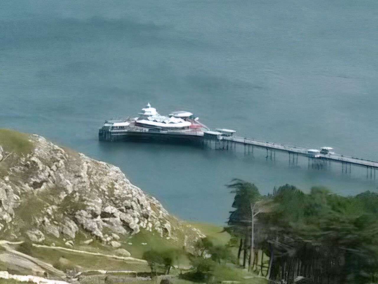 Ein Kreuzfahrtschiff liegt an einem Steg im ruhigen Wasser.
