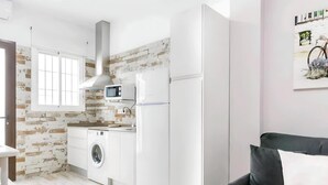 A compact kitchen with a washing machine, a microwave, and a refrigerator. - Cosy Apartment in Central Location (Conil de la Frontera)