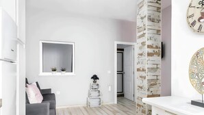 A modern living room with a grey sofa, a small round ottoman, a white coffee table, and a large mirror on the wall. - Cosy Apartment in Central Location (Conil de la Frontera)