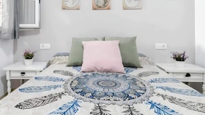 A bedroom with a bed, two nightstands, a window with curtains, and three wall-mounted artworks. - Cosy Apartment in Central Location (Conil de la Frontera)