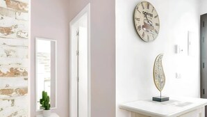 A room with a white door, a white table with a decorative object, and a wall clock. - Cosy Apartment in Central Location (Conil de la Frontera)