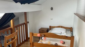 A cozy bedroom with a wooden bunk bed, a small bedside table, a chair, and a window with a view of the outdoors. - The Patou's house (Cadéac)
