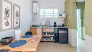 Una cucina compatta con zona pranzo, forno a microonde, macchina del caffè e frigorifero.