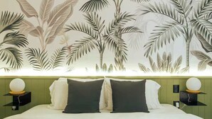 Una camera da letto con un letto, due comodini e una parete decorata con un motivo a foglia tropicale.
