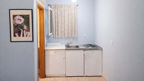 Pieni, käytännöllinen keittiö, jossa on pesuallas, liesi ja kaapit.