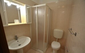 A bathroom with a sink, toilet, and a glass-enclosed shower. - Cozy Flat With Terrace and Pool Access (Lignano Sabbiadoro)