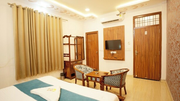 Une chambre d’hôtel avec un lit, un bureau avec des chaises, une télévision et des portes en bois.