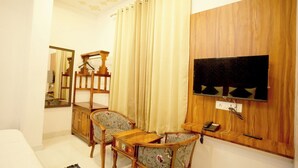 Un salon comprenant un meuble TV en bois, un canapé, deux fauteuils, un miroir et un rideau.