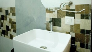 Une salle de bain avec un lavabo blanc, un miroir rond et un porte-serviettes.