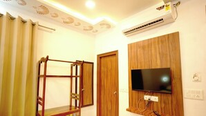 Une pièce avec une armoire en bois, un téléviseur fixé au mur et un ventilateur de plafond.