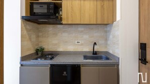 Cozinha compacta com micro-ondas, pia e lava-louças.