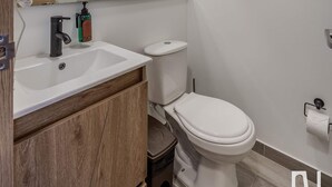 Uma casa de banho moderna com uma sanita, uma pia branca e um espelho grande.