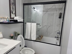 Une salle de bain moderne dotée d’une douche à parois de verre, de toilettes et d’un espace lavabo.