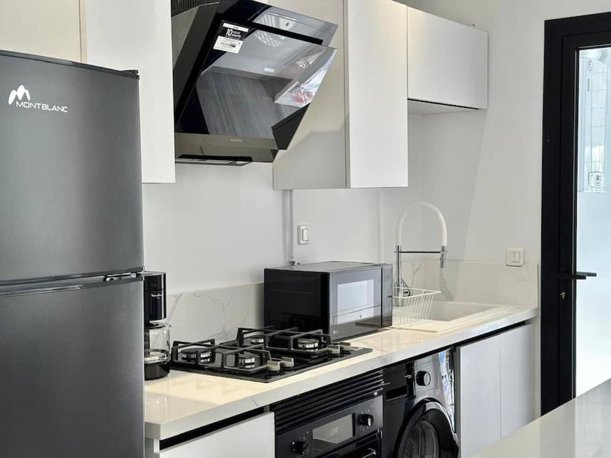 A modern kitchen with a refrigerator, microwave, gas stove, and a dishwasher.
