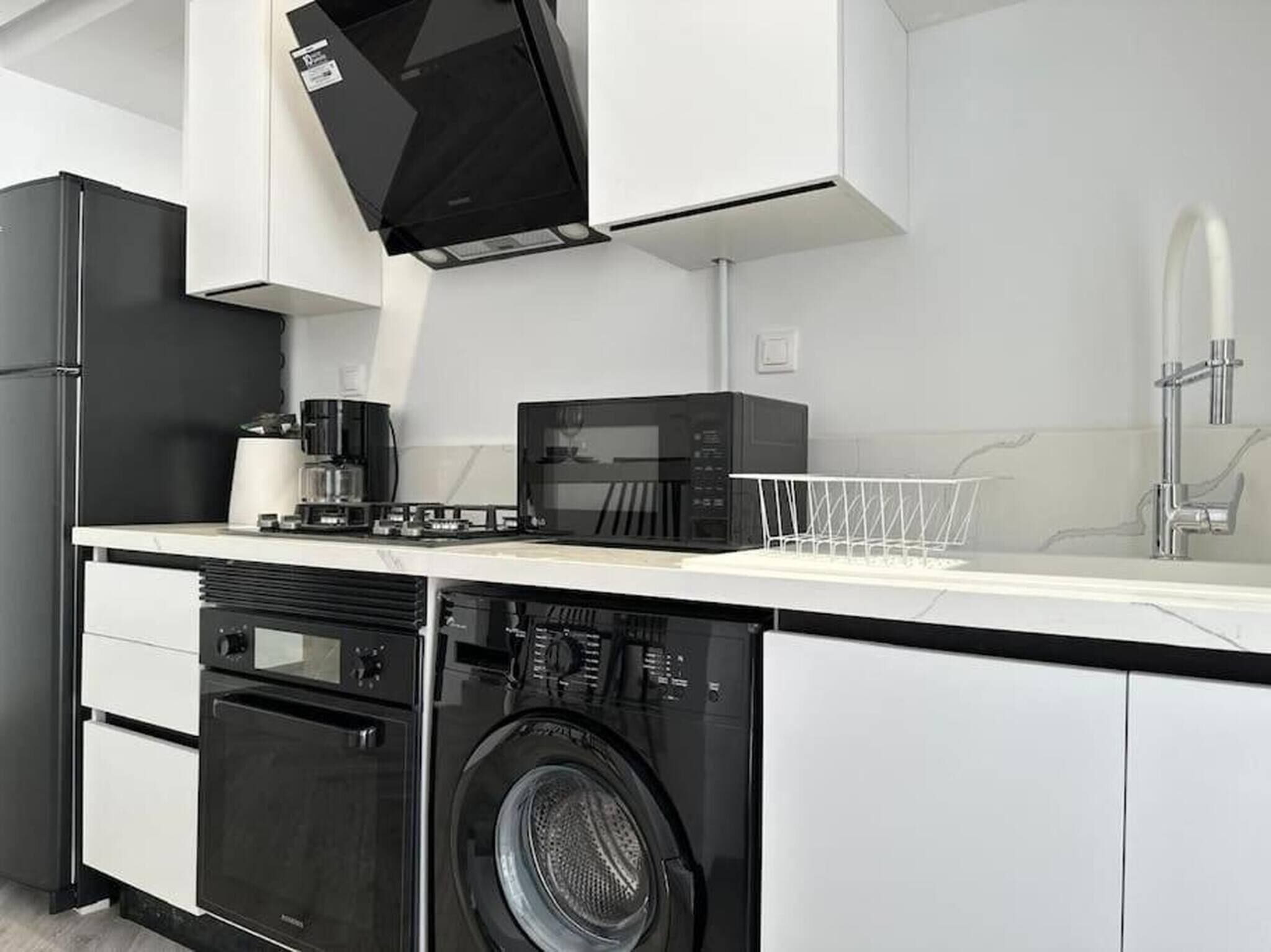 A modern kitchen with a built-in washer and dryer, a microwave, and a coffee maker.