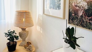 A room with a lamp, a small table with a potted plant, and two framed pictures on the wall. - Le Petit Cosy - King Size Bed, Quiet & Parking (Vaucelles)