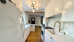 Una cocina moderna con armarios blancos, piso de madera e isla central.