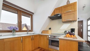 Een moderne keuken met houten kastjes, een inbouwoven en een groot raam.