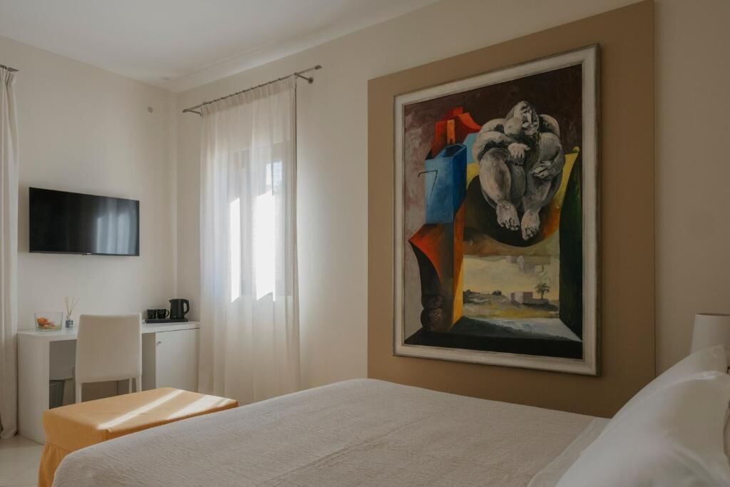 Une chambre d’hôtel comprenant un lit, un bureau avec une chaise, un téléviseur fixé au mur et un tableau accroché au mur.