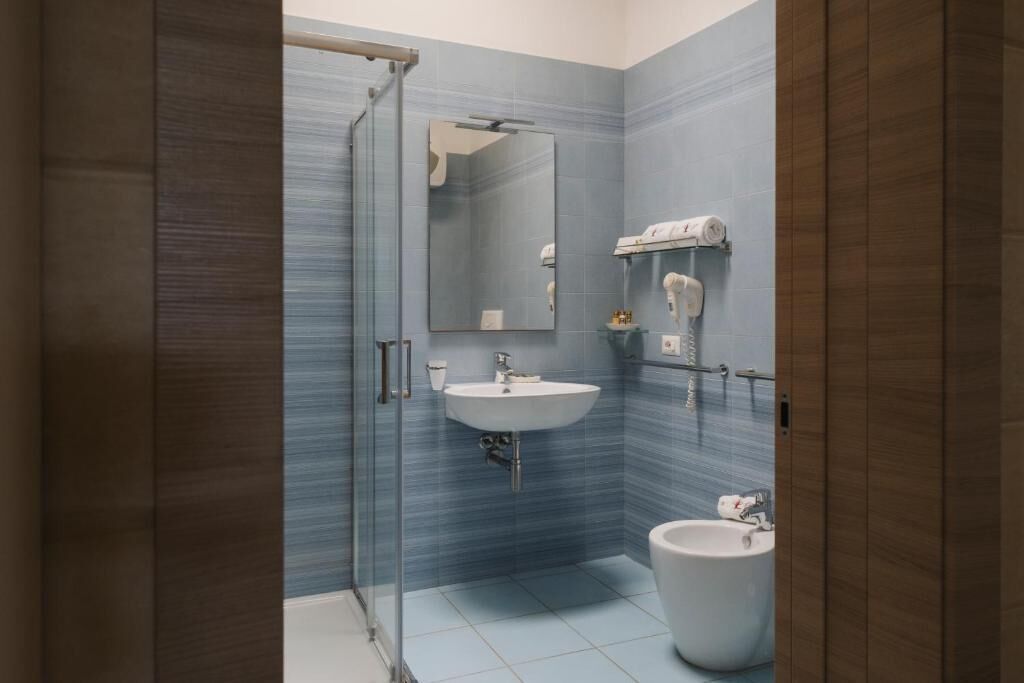 A modern bathroom with a glass shower enclosure, a sink, and a bidet.