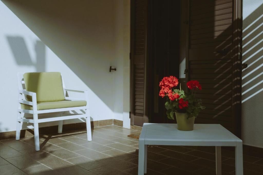 A small room with a white chair, a small table with a potted plant, and a door with a window.