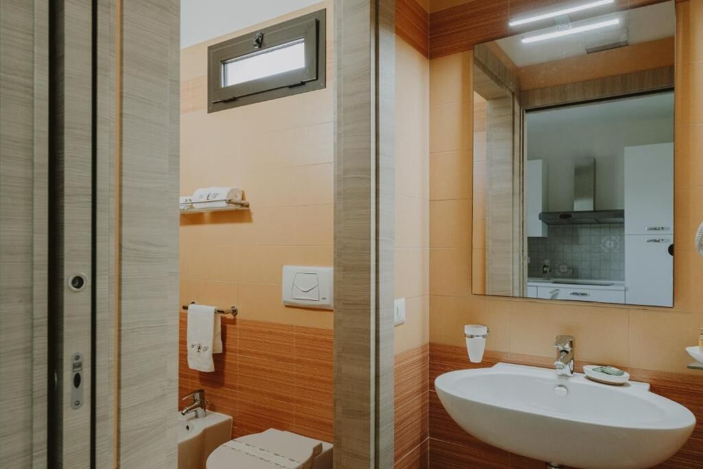A modern bathroom with a large sink, a mirror, and a towel rack.