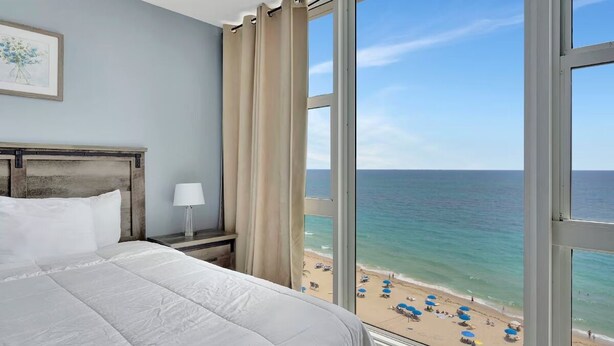 Une chambre d’hôtel avec une grande fenêtre donnant sur une plage.