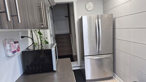 A modern kitchen with stainless steel appliances, a built-in microwave, and a first aid kit on the wall.